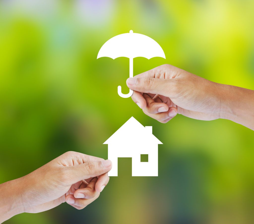Paper umbrella covering paper house depicts home insurance coverage